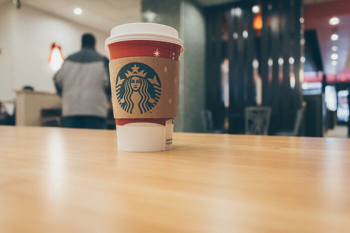 Starbucks coffee cup on a wooden table in a cafe, illustrating unhealthy habits people have seen others do.