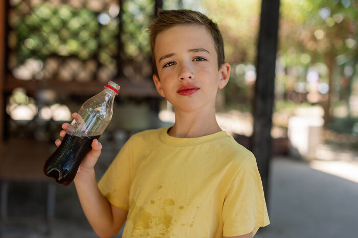 Young boy with stained shirt drinking soda, illustrating unhealthy habits and behaviors people have witnessed.