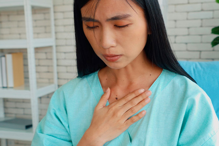 Woman in a medical gown with hand on chest, illustrating healthcare worker analogies for medical problems.