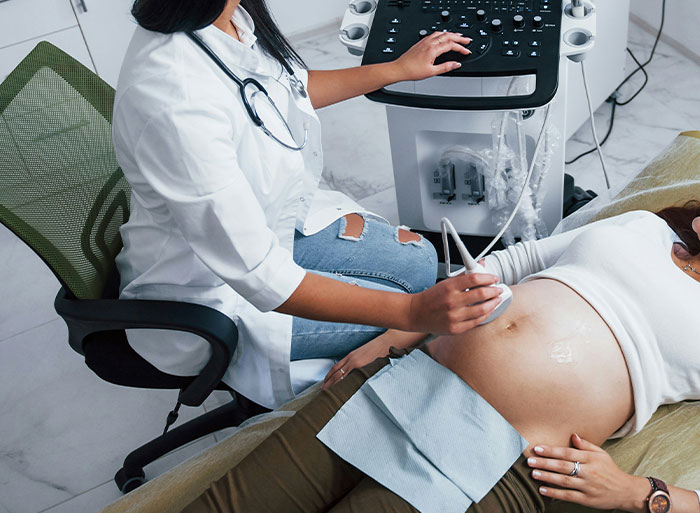 Healthcare worker performing an ultrasound on a pregnant woman, illustrating medical problems with wild analogies.