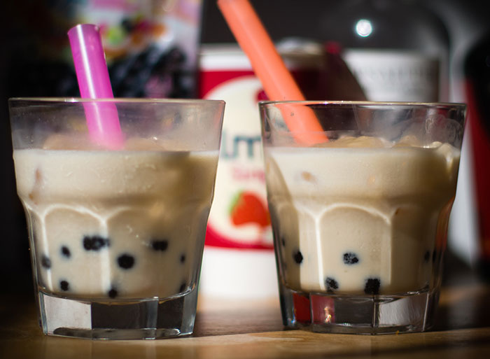 Two glasses of bubble tea with colorful straws on a wooden table, highlighting wild analogies healthcare workers use.