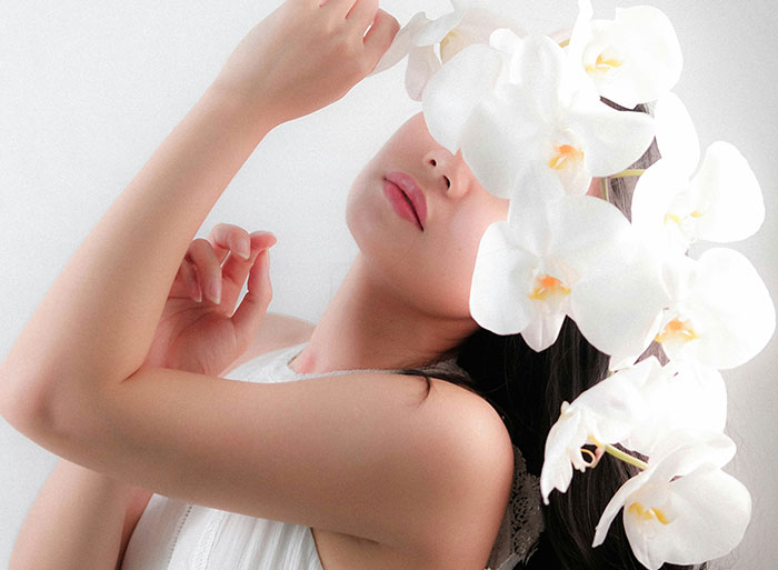Woman with white orchids covering her face, representing wild analogies healthcare workers use to explain medical problems.