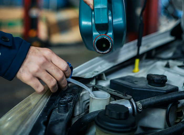 Hand pouring fluid into car engine, illustrating wild analogies healthcare workers use to explain medical problems.