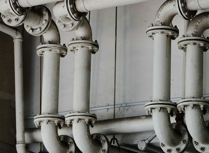 Close-up of white industrial pipes illustrating wild analogies healthcare workers use to explain medical problems.