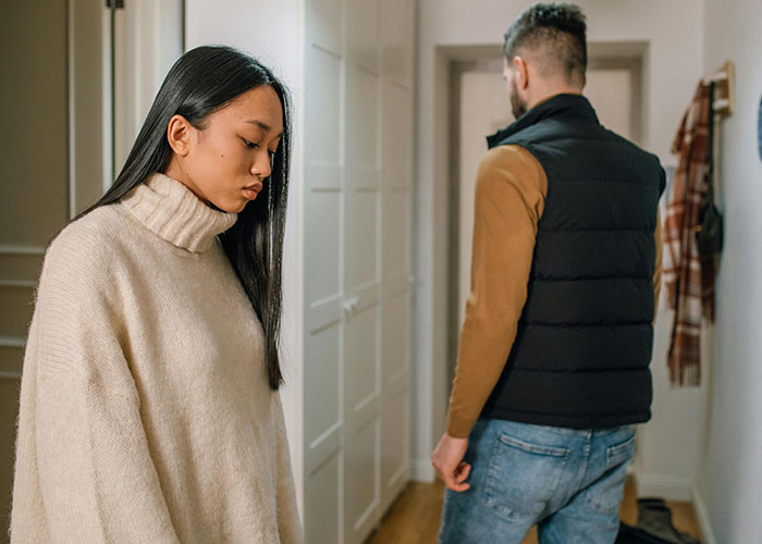 Couple facing away from each other in a hallway, reflecting tension after discovering rent has been paid unknowingly.