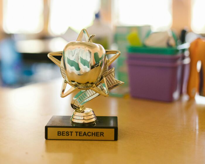 Golden best teacher trophy in the shape of an apple and star, symbolizing teacher appreciation week deals and special offers.