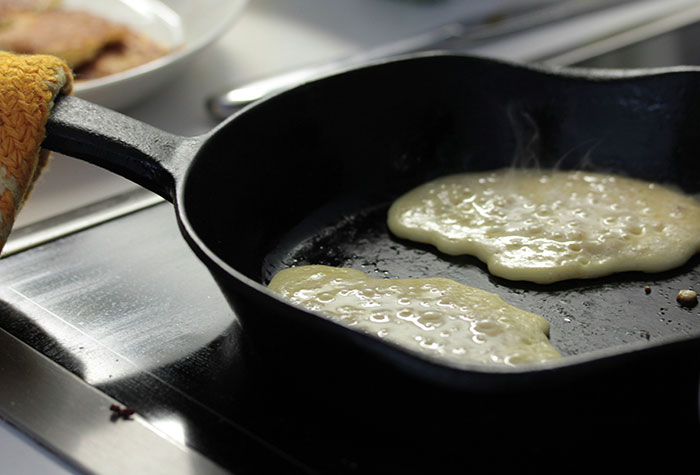 Pancakes cooking on a black cast iron skillet on a stove, illustrating common cooking advice and techniques.