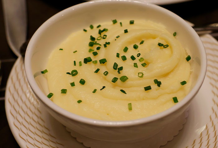 Bowl of creamy mashed potatoes garnished with chopped chives, illustrating common cooking advice shared by people.