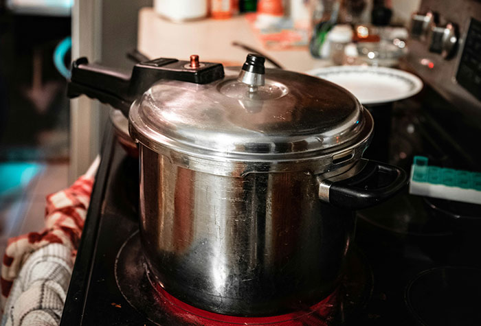 Pressure cooker on stove with stovetop burner on, illustrating common cooking advice and kitchen techniques.