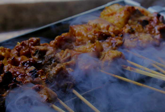 Grilled skewers cooking on a smoky grill showing common cooking advice in a casual outdoor setting.