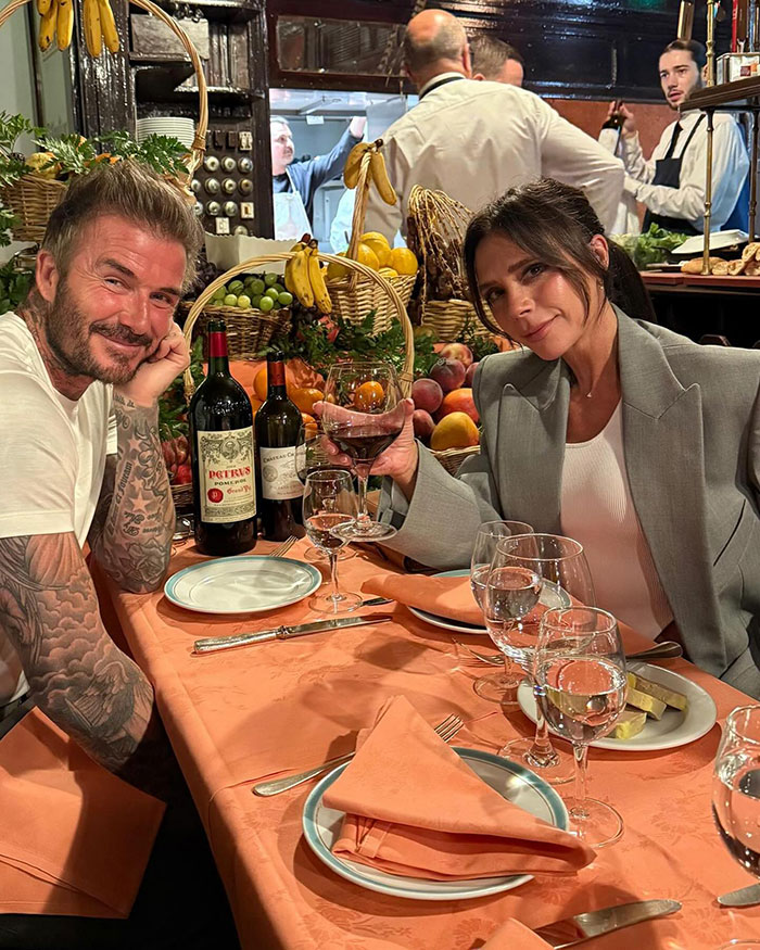 David Beckham and Victoria Beckham at a dinner table with wine and fruit, amid birthday party family feud rumors.