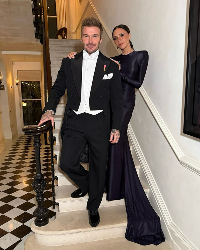 David Beckham in formal wear posing on stairs with a woman, highlighting narcissistic label amid family feud rumors.