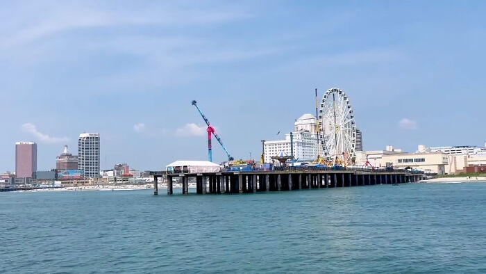 Seaside tourist destination with a pier and ferris wheel, representing popular tourist destinations fallen into oblivion.