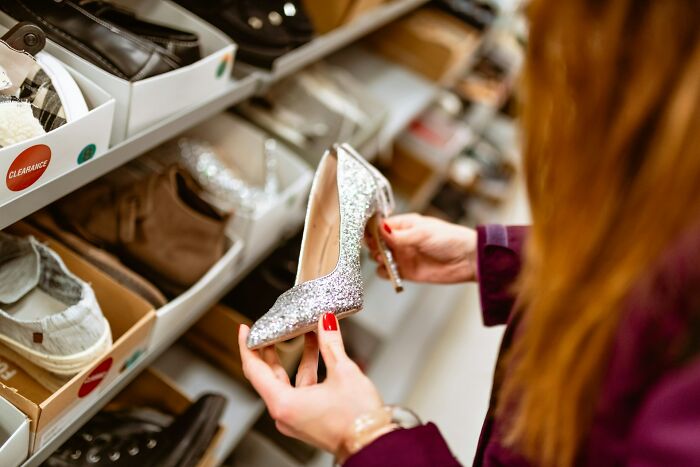 Woman holding a glittery high heel shoe in a retail store, revealing industry secrets behind closed doors in fashion.