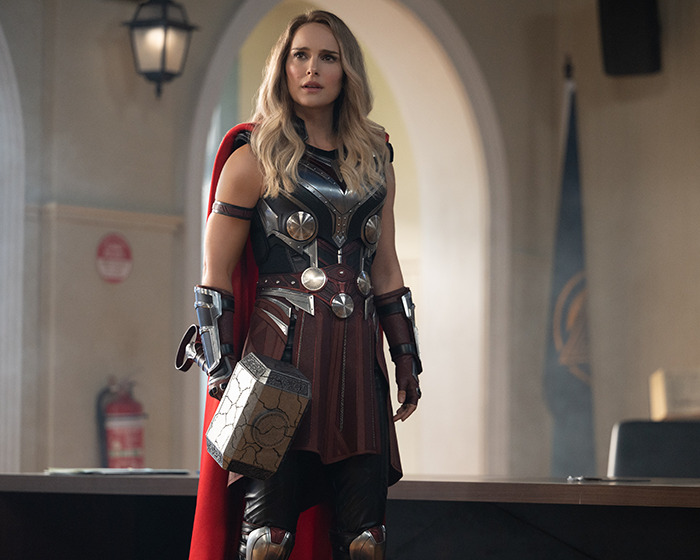 Woman dressed as Thor holding a hammer, representing an A-List star in a vlogger scenario without realizing her presence.