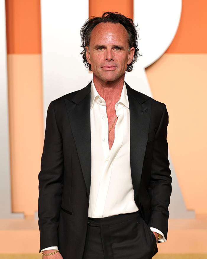 Walton Goggins in a black suit and white shirt at an event, reacting to Aimee Lou Wood feud questions.