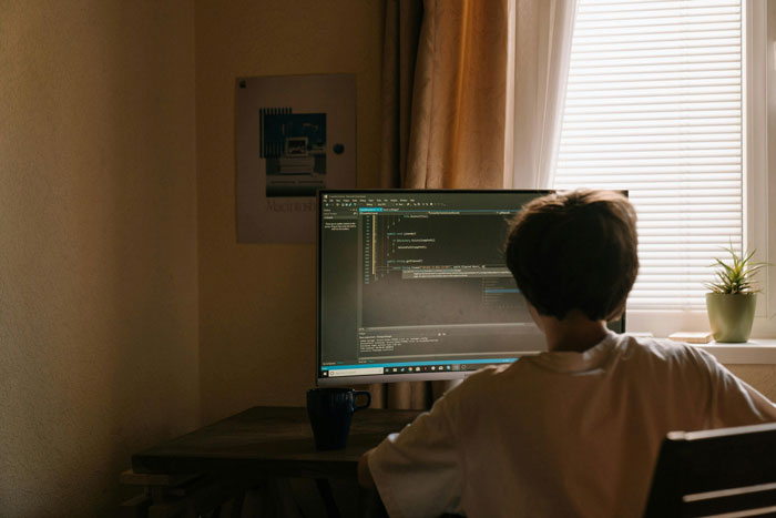 Freelancer working on code by computer screen in dim room, illustrating client fails to pay and payment trick.