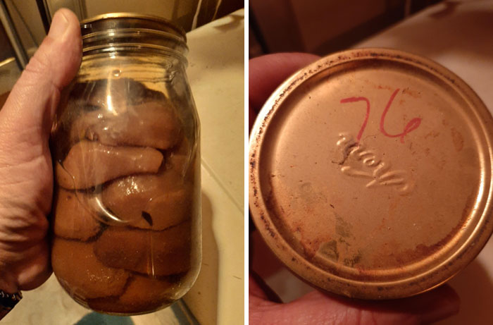 Hand holding a jar of preserved first prize string beans with a rusty metal lid marked 76 inside an old house.