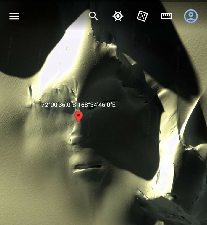 Satellite view showing an odd land formation with shadows and coordinates, an example of strange finds on Google Earth.