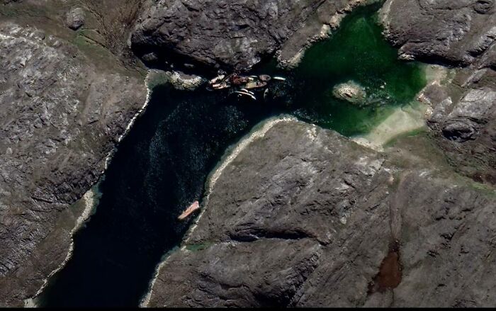 Aerial view of a rocky coastline with a narrow water inlet showing odd objects found on Google Earth.