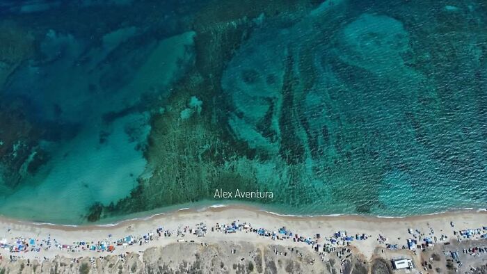Aerial view of a beach with clear ocean water revealing unusual shapes, showcasing odd things found on Google Earth.