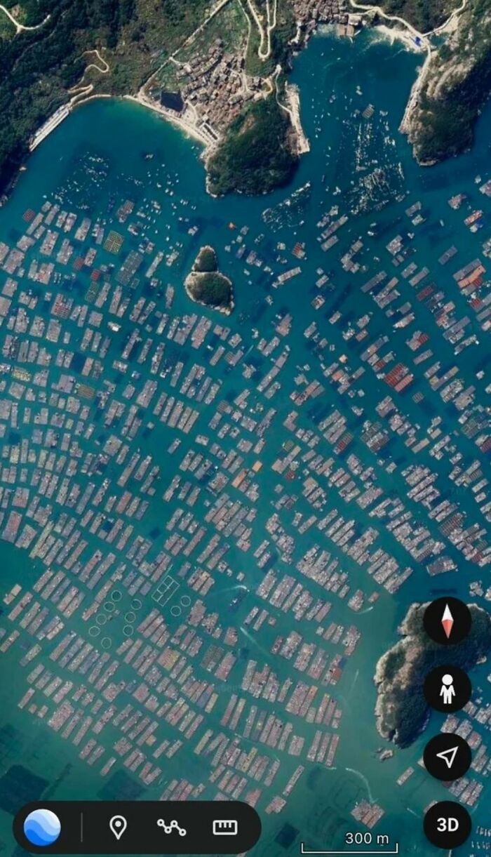 Aerial view of a dense floating village with many boats and structures on water, an odd finding on Google Earth.