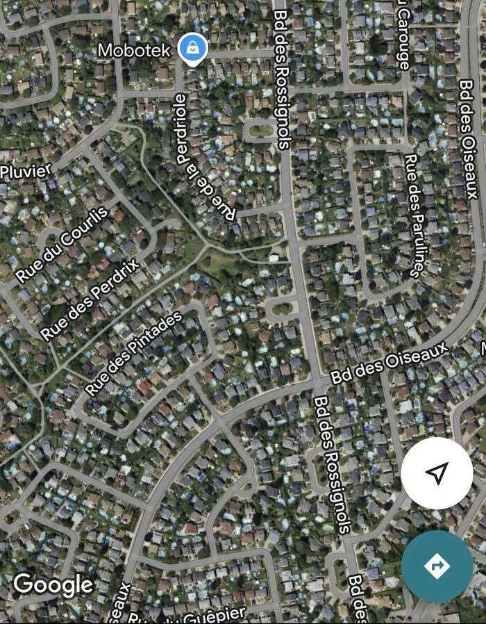 Aerial view of a dense residential neighborhood captured on Google Earth, showing streets and houses.