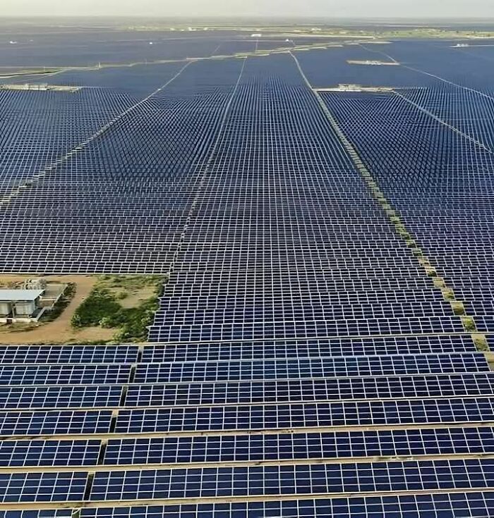 A vast solar panel farm with thousands of panels arranged in geometric patterns visible on Google Earth.