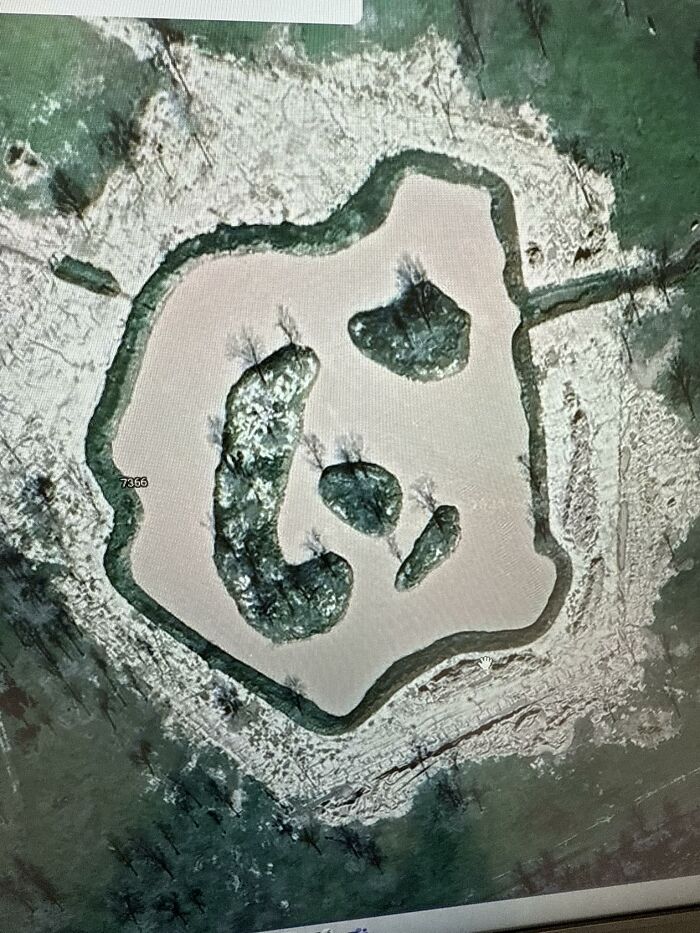 Aerial view of a frozen pond with islands forming an odd face shape, an unusual Google Earth discovery.
