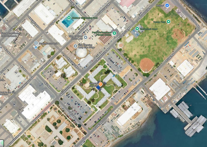 Aerial view of a coastal city layout with buildings, parking lots, and a baseball field, showing weird things on Google Earth.