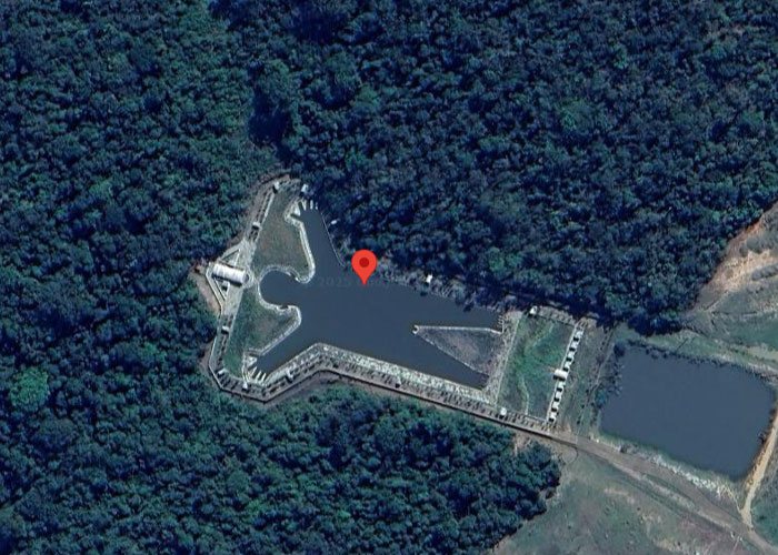 Aerial view of a strange structure resembling an airplane shape surrounded by dense forest on Google Earth.