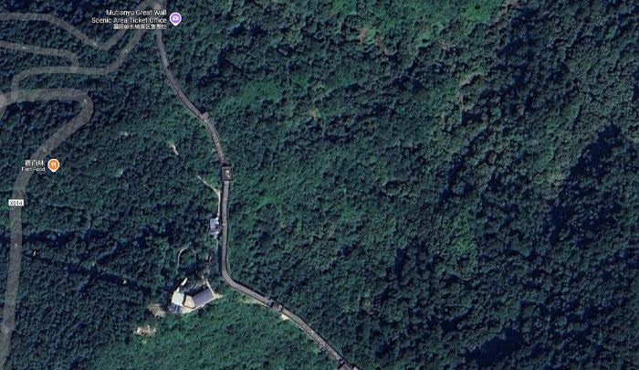 Aerial view on Google Earth showing dense forest with winding road near Mutianyu Great Wall scenic area ticket office.