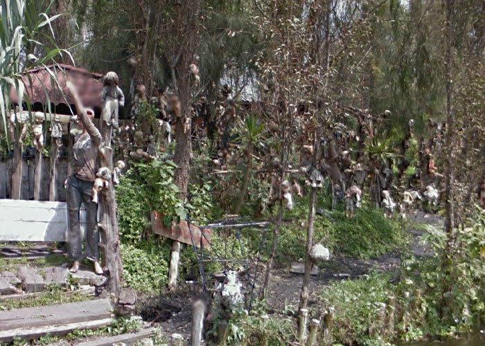 Creepy dolls hanging from trees in an eerie outdoor scene, one of the weird things on Google Earth places.