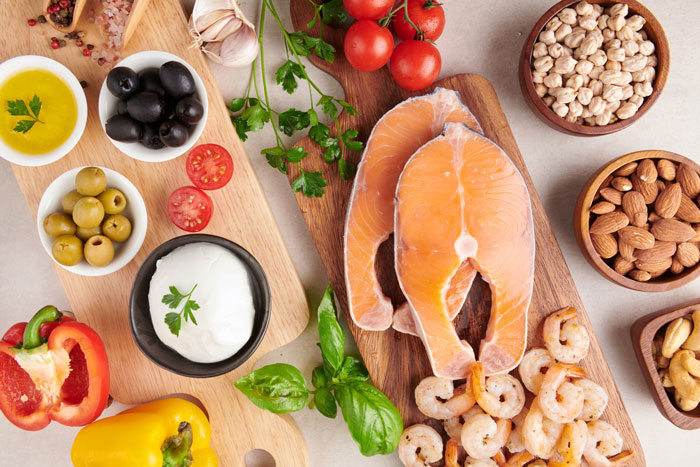 Fresh salmon, shrimp, nuts, olives, and vegetables displayed as healthy food options to burn fat better with Ozempic.