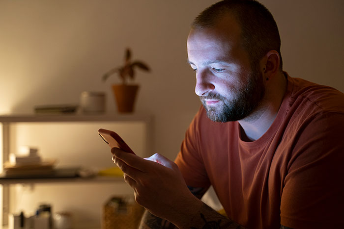 Man focused on his phone at night, highlighting a husband busy with TikTok while wife is scared and bruised in ER.