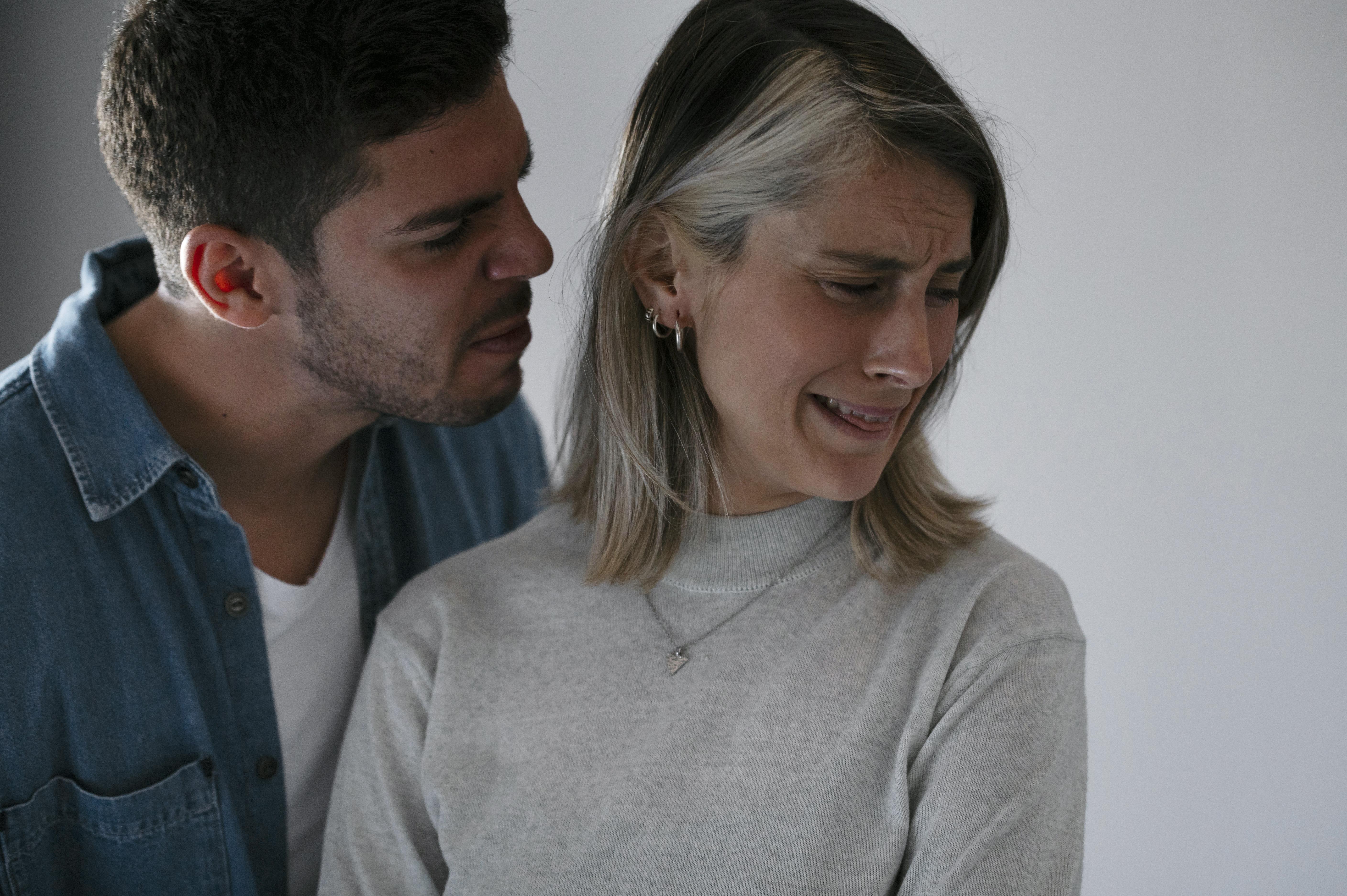 Woman crying while man comforts her, illustrating the emotional impact of a heartbreaking cancer diagnosis.