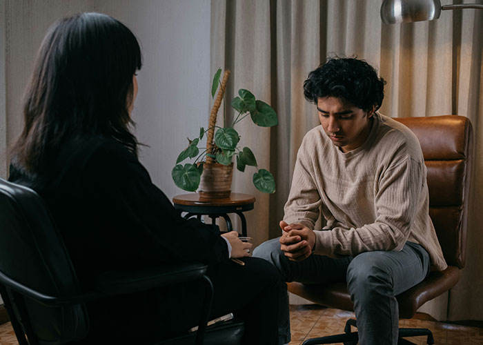 Wife and husband in tense conversation at home, wife refuses to support husband&rsquo;s mom after job loss discussion.