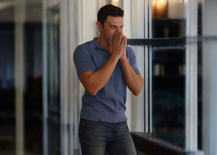 Man in a blue shirt looking stressed indoors, illustrating a husband facing job loss and family support conflict.