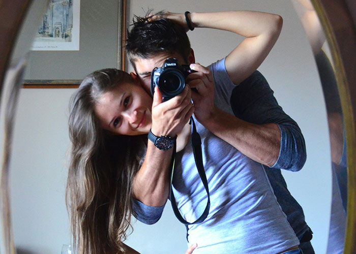 Man and woman posing closely for mirror selfie as part of a fake relationship to make people think she cheated.