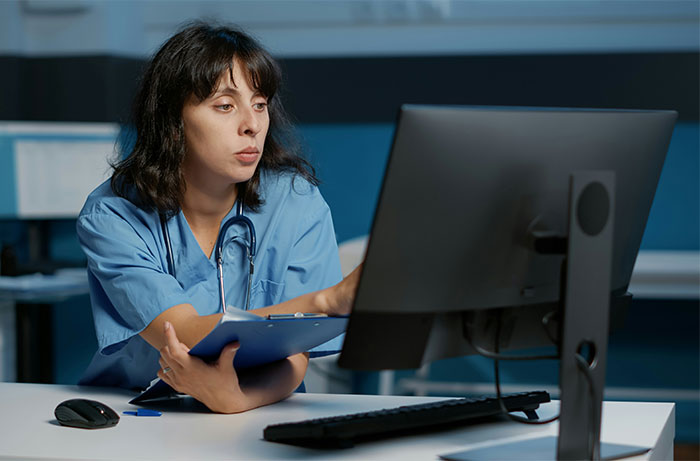 Woman in medical scrubs working on a computer, representing a strong woman shutting down MIL and calling her a gold digger housewife.