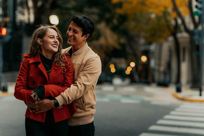 Man hugs woman on city street during autumn, illustrating family reaction to mom leaving little sisters alone.