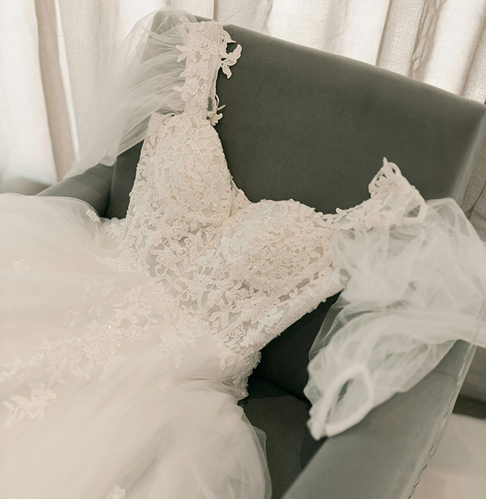 Lace wedding dress with veil laid on chair symbolizing refusal to wear fianc&eacute;&rsquo;s mom&rsquo;s used dress.