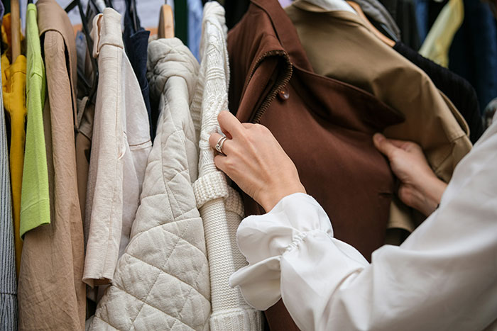 Woman browsing clothes in a closet, illustrating new trends amid predictions of a US recession.