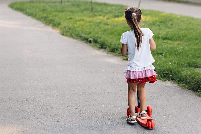 Young girl riding a scooter on a path, illustrating babysitting and vacation with boyfriend’s niece concept. Young girl riding a scooter on a path, illustrating babysitting and vacation with boyfriend’s niece concept.