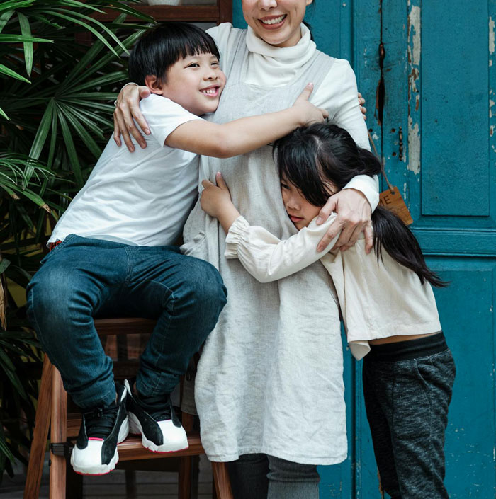 Woman hugs two children, illustrating a babysitter situation involving husband's ex as a possible option.