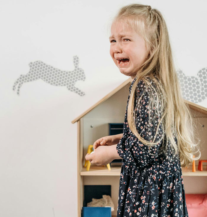 Crying young girl indoors, illustrating conflict in woman refusing to take sister&rsquo;s kid on trips causing family tension.