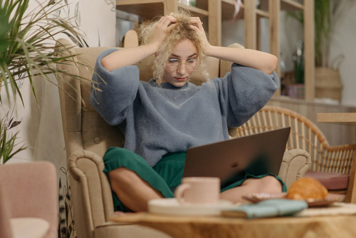 Young woman looking stressed during an interview task on laptop, realizing she got tricked while working from home. Young woman looking stressed during an interview task on laptop, realizing she got tricked while working from home.