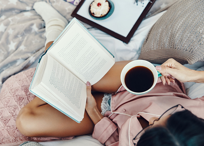 Woman enjoying alone time reading a book and drinking coffee, illustrating why women love being alone peacefully.