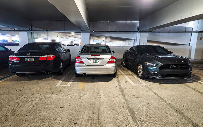 Three cars parked in a covered lot illustrating unhinged safety habits shared by women that might actually save lives.