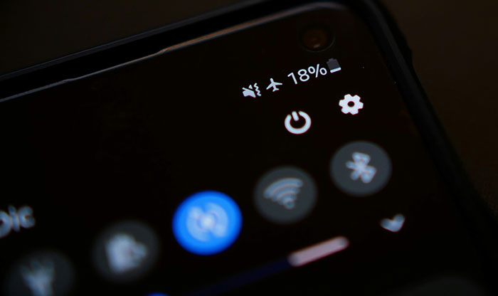 Close-up of a phone screen showing low battery and wireless connectivity icons illustrating unhinged safety habits.